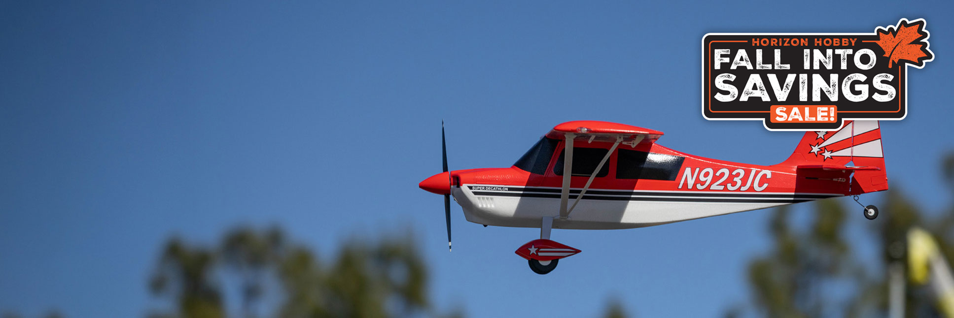 Action shot of the E-flite Super Decathlon 1.2m Bind-N-Fly Basic with AS3X+ and SAFE Select RC airplane flying through the sky with the Horizon Hobby Fall Into Savings Logo