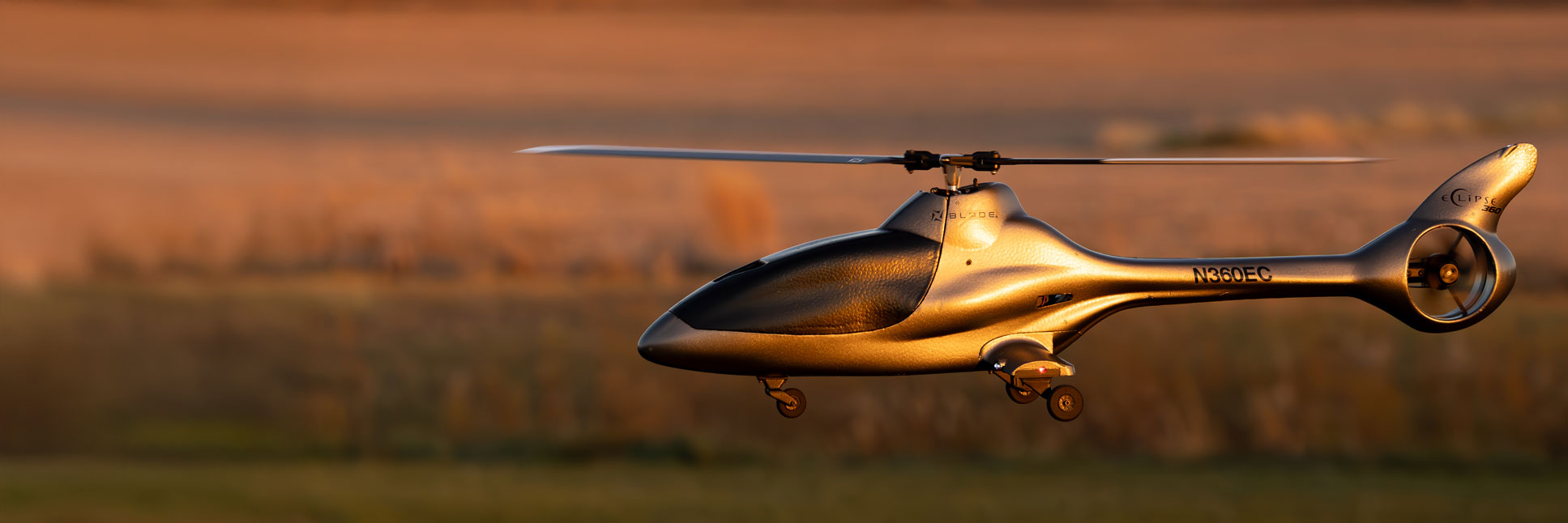 Action shot of the Blade Eclipse 360 BNF Basic RC Helicopter with AS3X and SAFE hovering in the air above grass