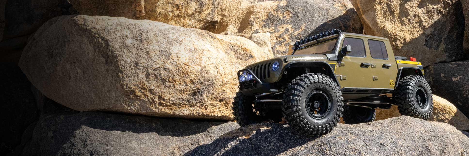 Action shot of the Axial 1/10 SCX10 III Motobilt Waypoint Jeep JT Gladiator 4X4 Ready-To-Run Brushed Rock Crawler climbing over boulders Action shot of the Axial 1/10 SCX10 III Motobilt Waypoint Jeep JT Gladiator 4X4 Ready-To-Run Brushed Rock Crawler climbing over boulders