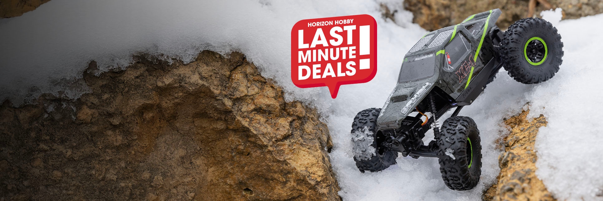 Action shot of the Axial 1/24 AX24 XC-1 4WS 4X4 Ready-To-Run Brushed RC Rock Crawler crawling over rocks and snow with the Last Minute Deals logo