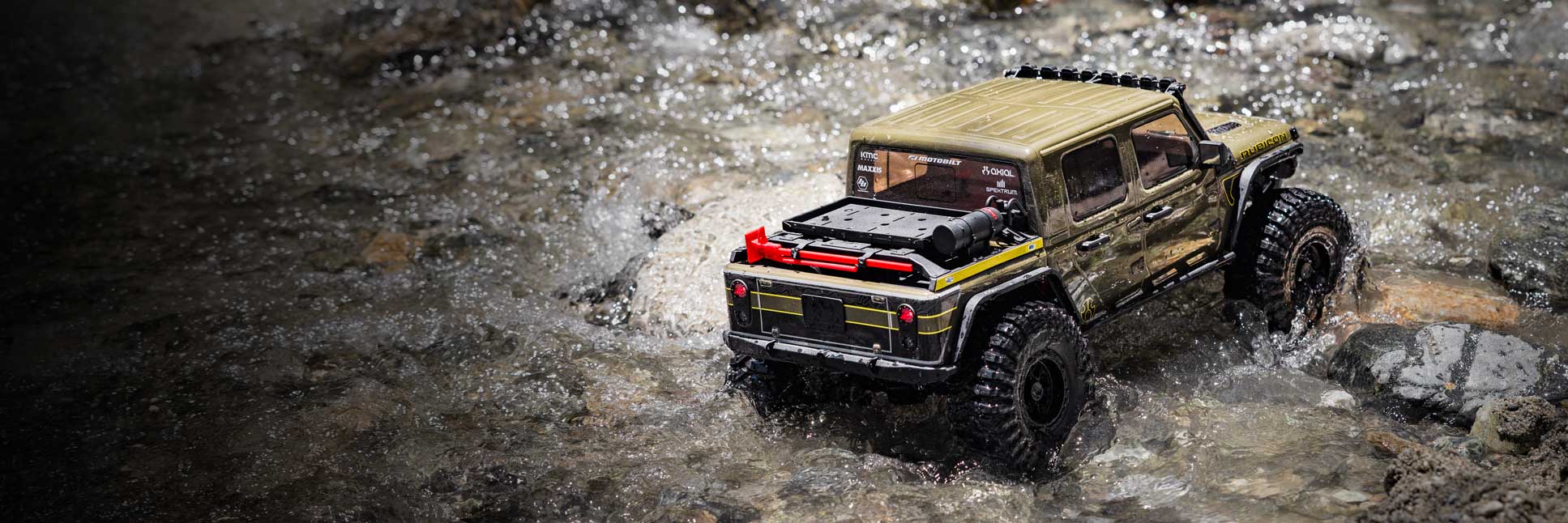 Action shot of the Axial 1/10 SCX10 III Motobilt Waypoint Jeep JT Gladiator 4X4 Ready-To-Run Brushed Rock Crawler climbing over boulders