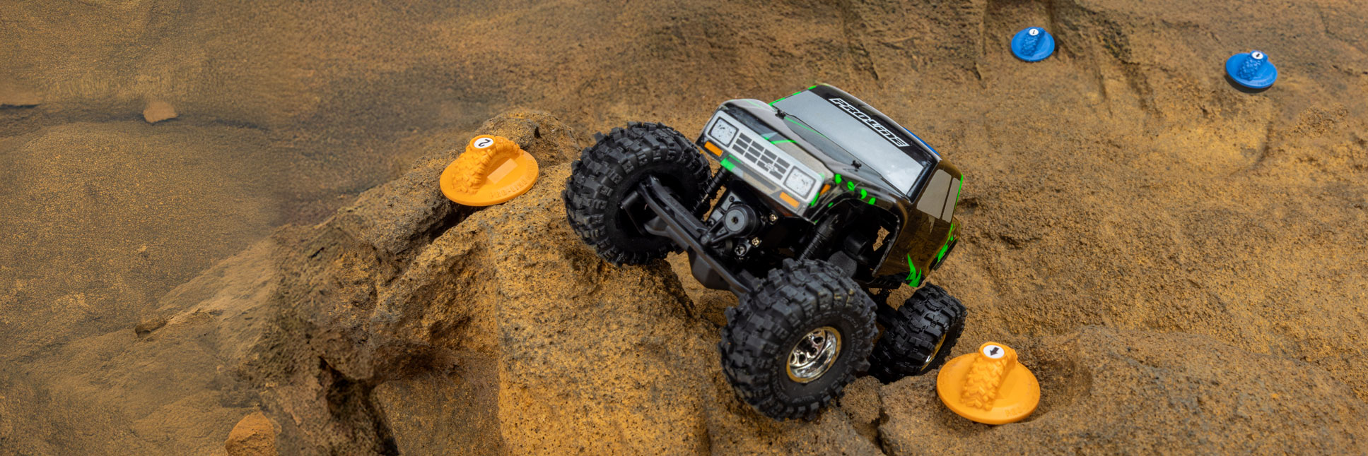 Action shot of the Pro-Line Blue and Orange Gate Marker Set used as a course route on a rocky surface to define direction for a RC rock crawler Action shot of the Pro-Line Blue and Orange Gate Marker Set used as a course route on a rocky surface to define direction for a RC rock crawler