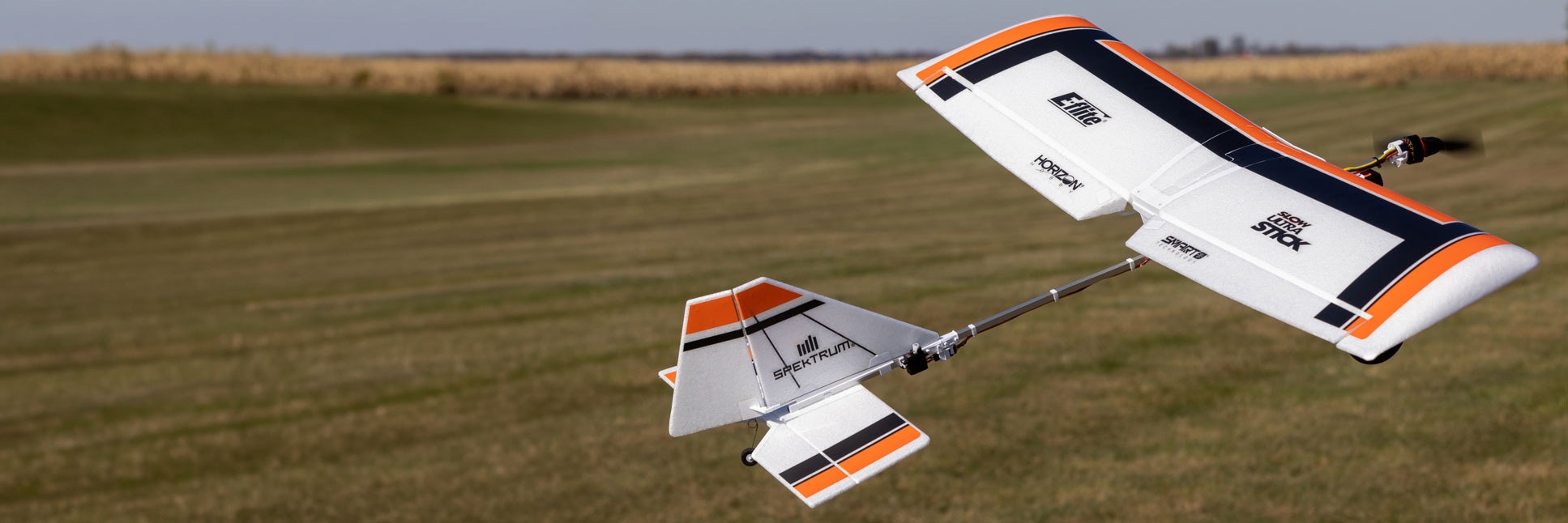 Action shot of the E-flite Slow Ultra Stick 1.2m BNF Basic with AS3X and SAFE Select RC Aircraft flying through the air above a grassy field