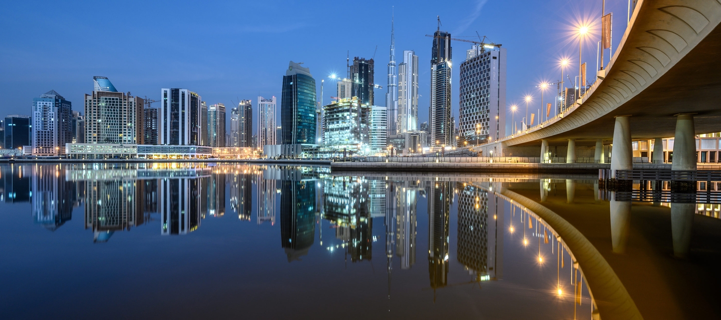 Low light image of a city and its reflection in water, captured with the NIKKOR Z 14-30mm f/4 S lens