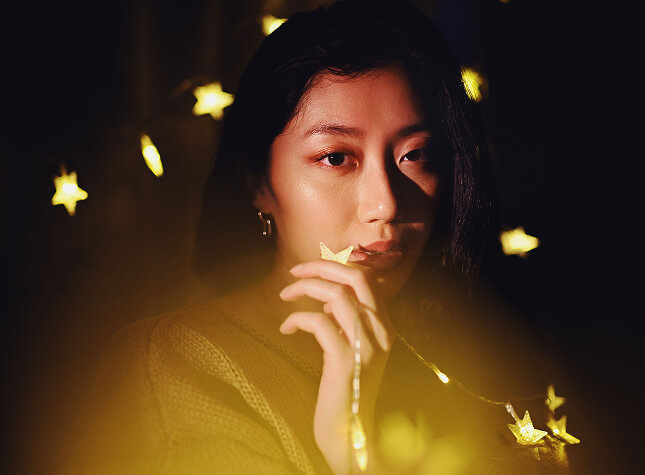 Portrait photograph of a young woman in a yellow knitted sweater.