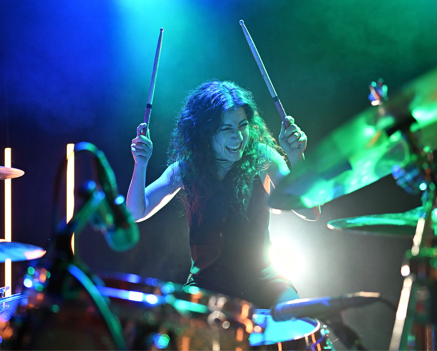 A female drummer holding drumsticks mid-performance, highlighting Z5II's low light capabilities.