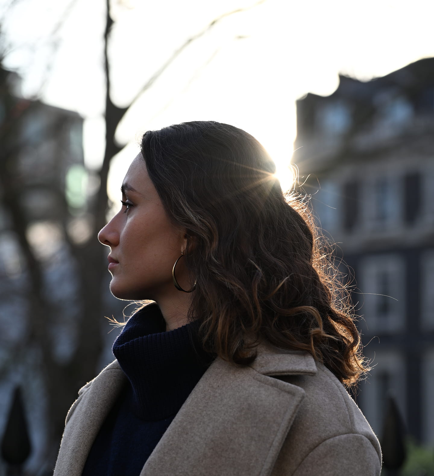 An in-focus woman in the foreground looks to the distance with out-of-focus buildings in the background, highlighting Z5II's autofocus capabilities.