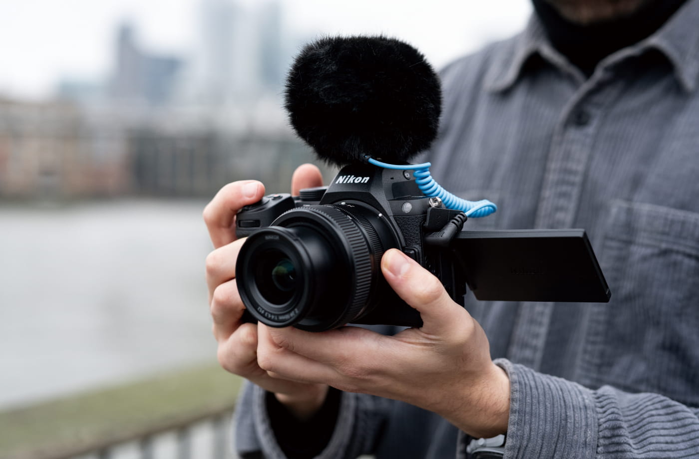 A videographer recording with the Z5II and an external microphone, using the vari-angle display as a monitor.