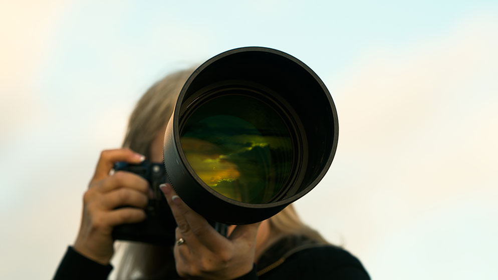 photo of a person looking through a camera and large lens