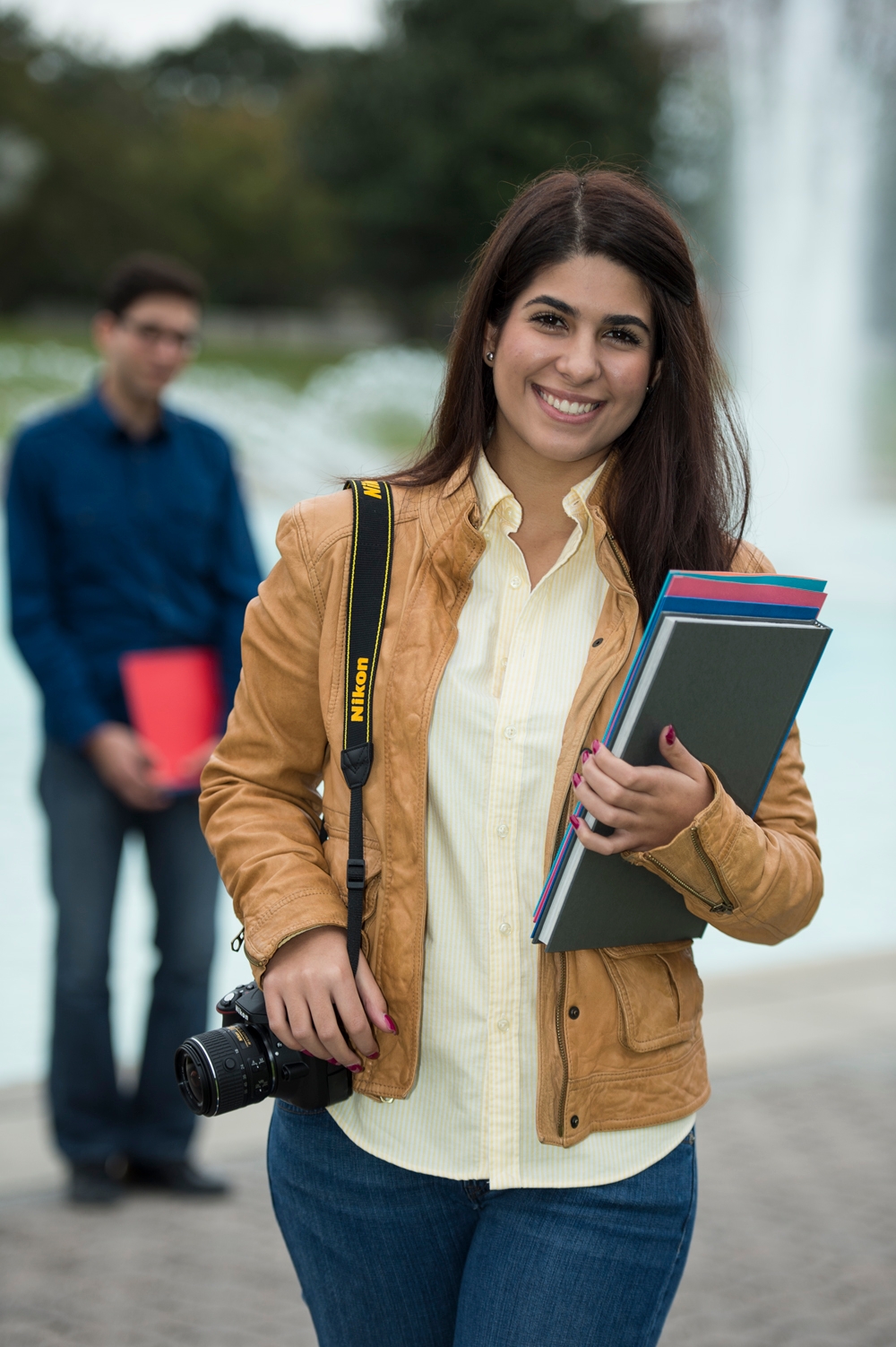 photo of a woman with her camera on her shoulder and a guy out of focus in the background