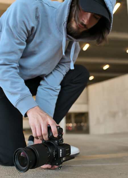 A male photographer holds the Z5II sideways near the ground, using the vari-angle monitor to view his subject.