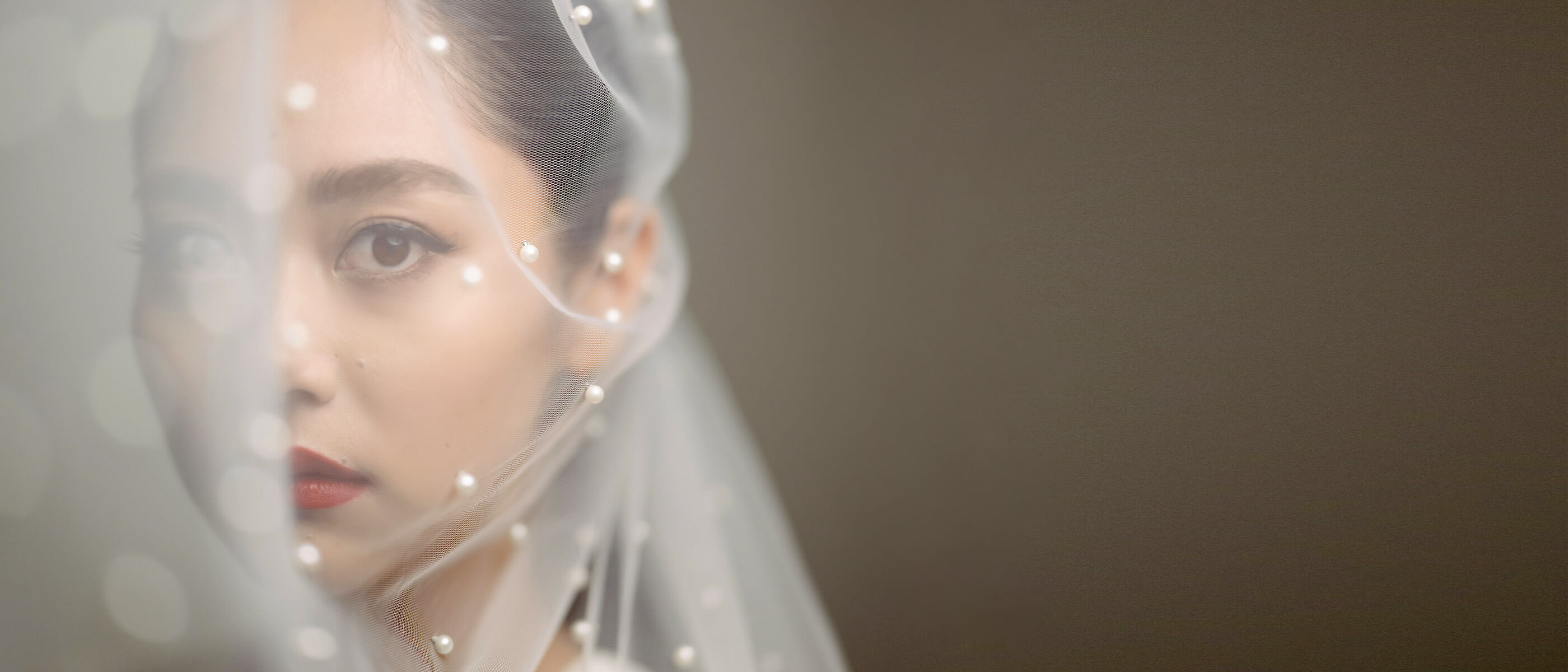 Photo of a bride behind a veil looking at the camera, taken with the NIKKOR Z 85mm f/1.2 S lens