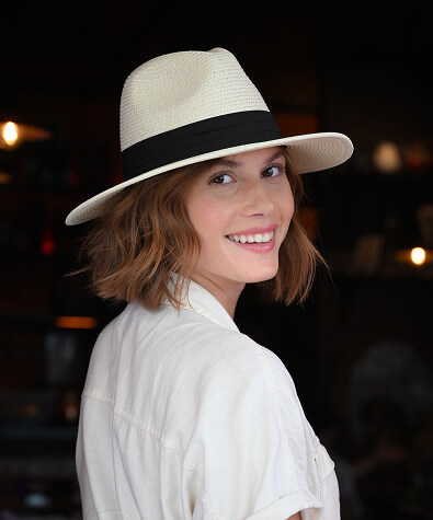 A woman in a white shirt and hat looks over her shoulder toward the camera.