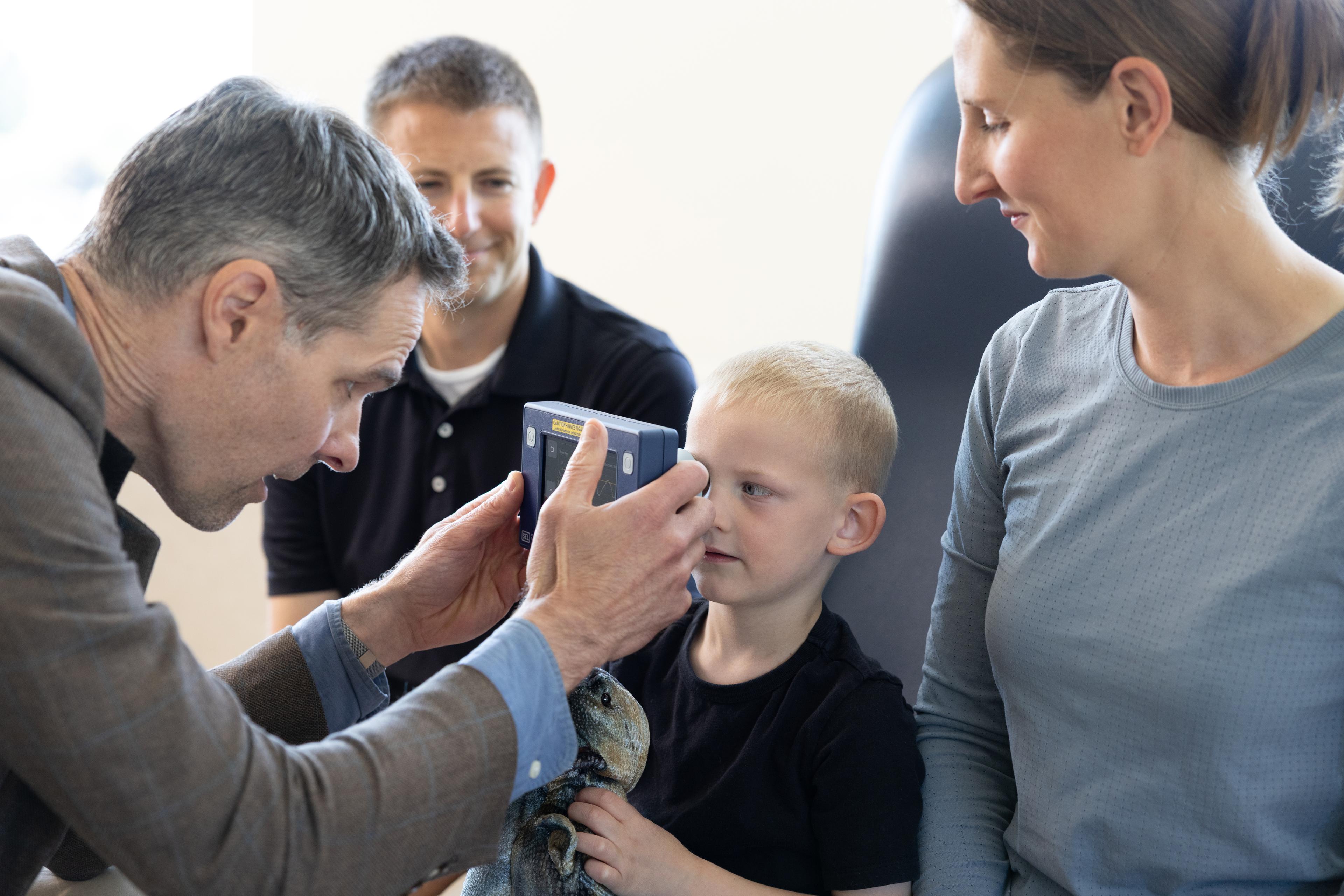 Clinician using a handheld pupillometer to examine a child's eye.