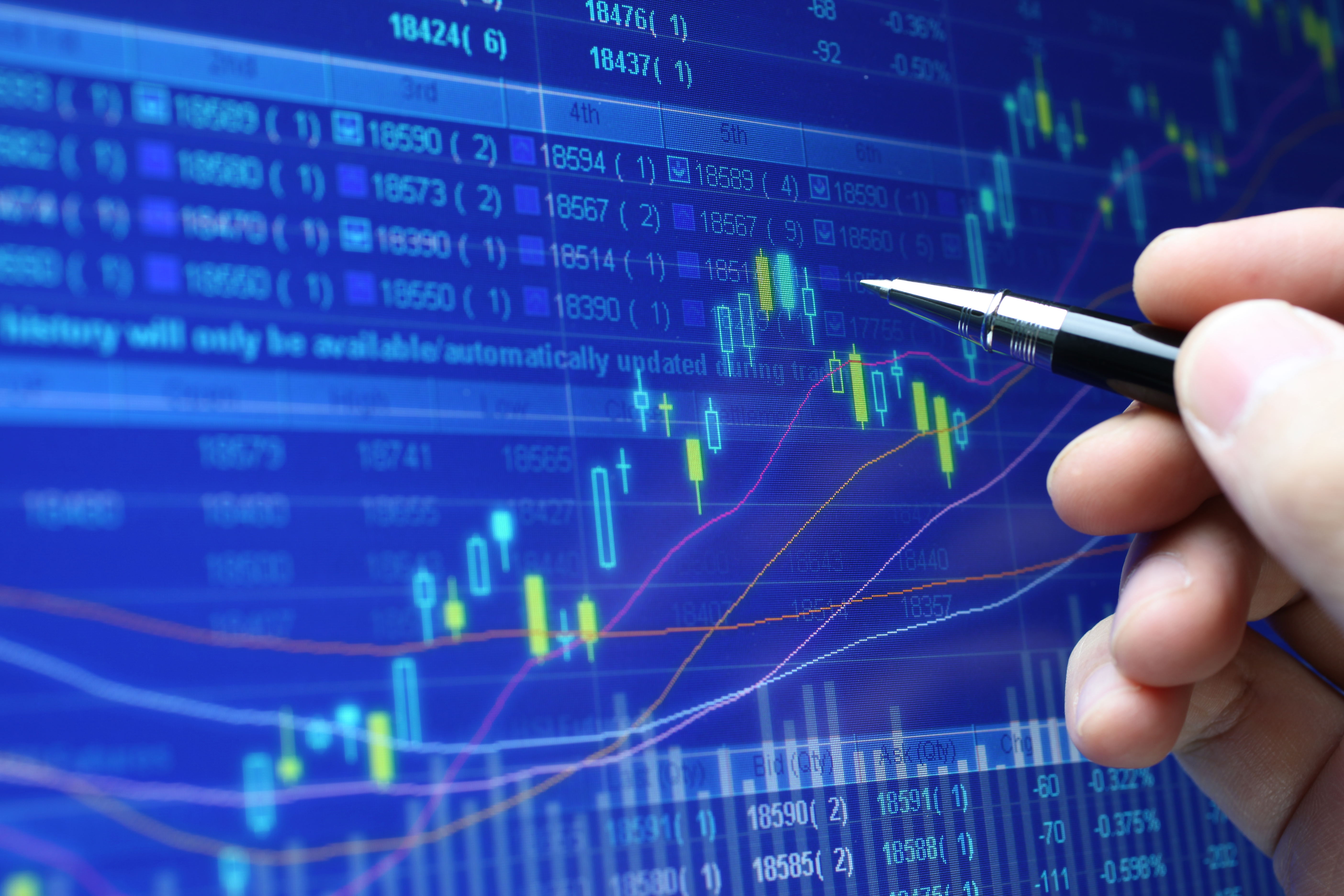 Close-up of pen indicating trends in a digital data graph.