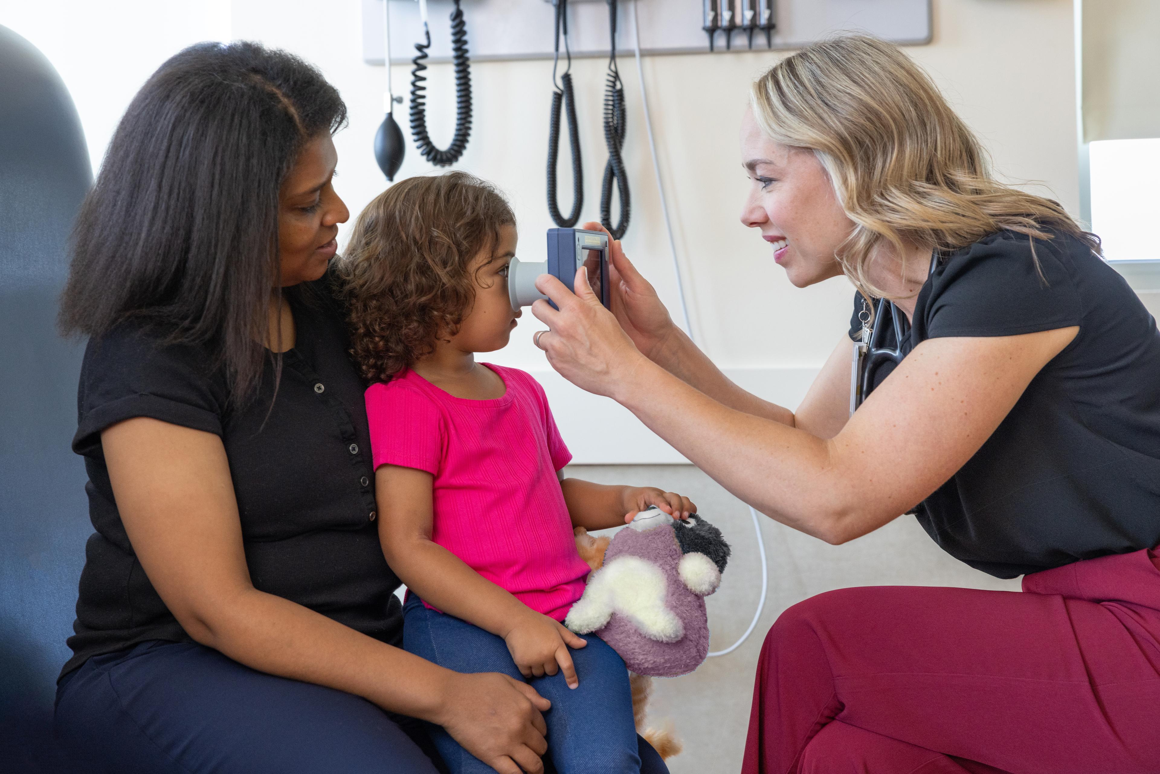 Child undergoing pupillary light reflex measurement with a handheld device.