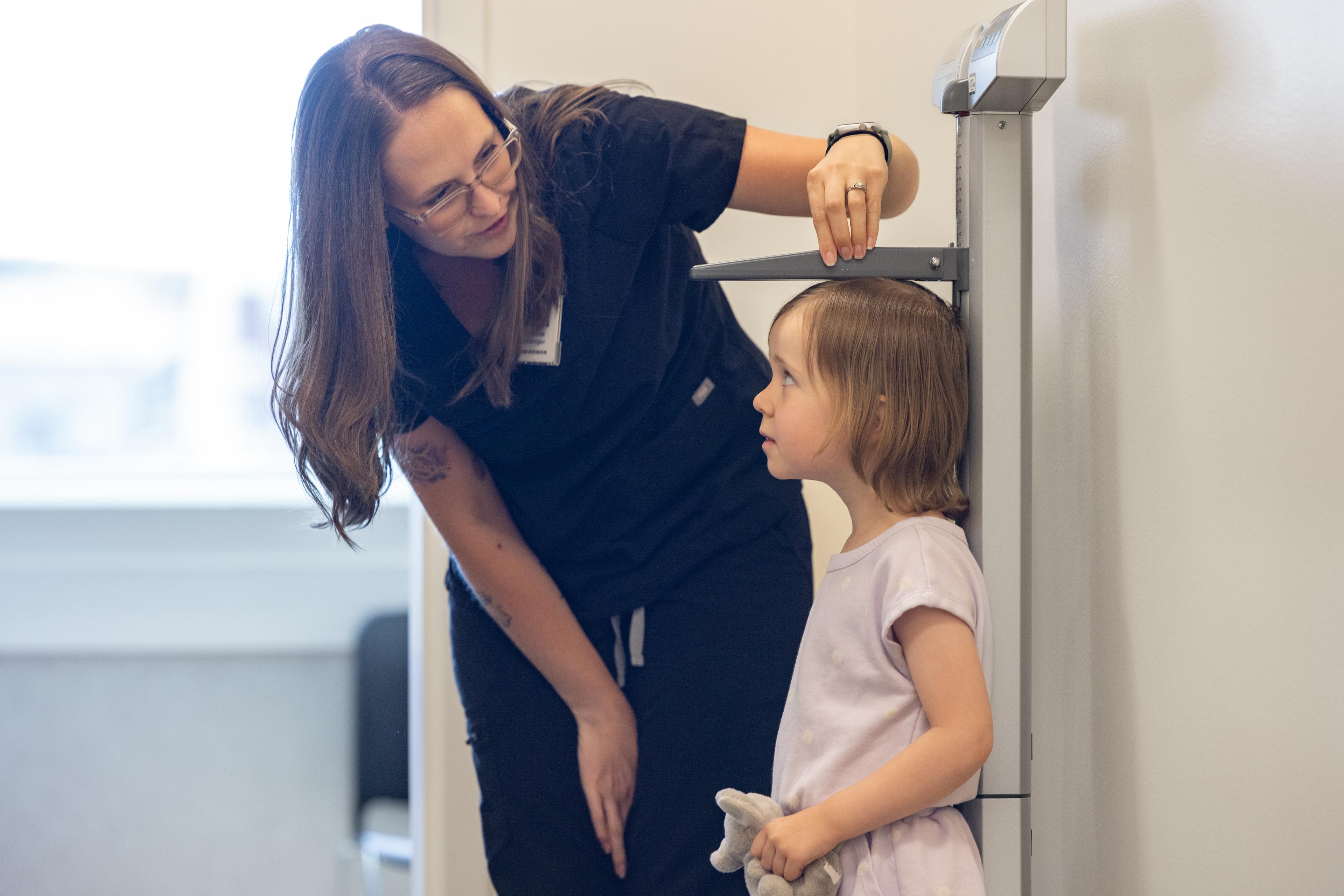 Healthcare professional measuring a child's height during a clinic visit.