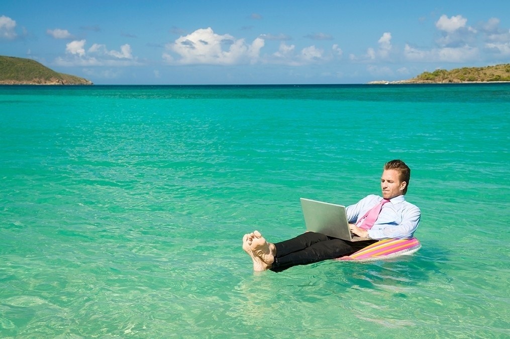 man on laptop on a raft in the ocean