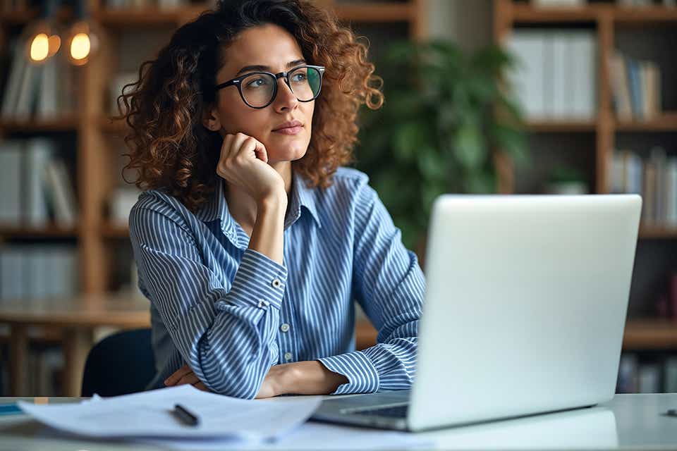 woman gazing off into space in front of a computer