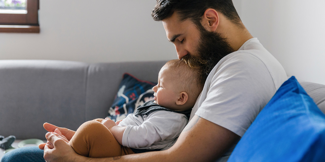 A man holding his young child thinking about how to loan money to family and friends.