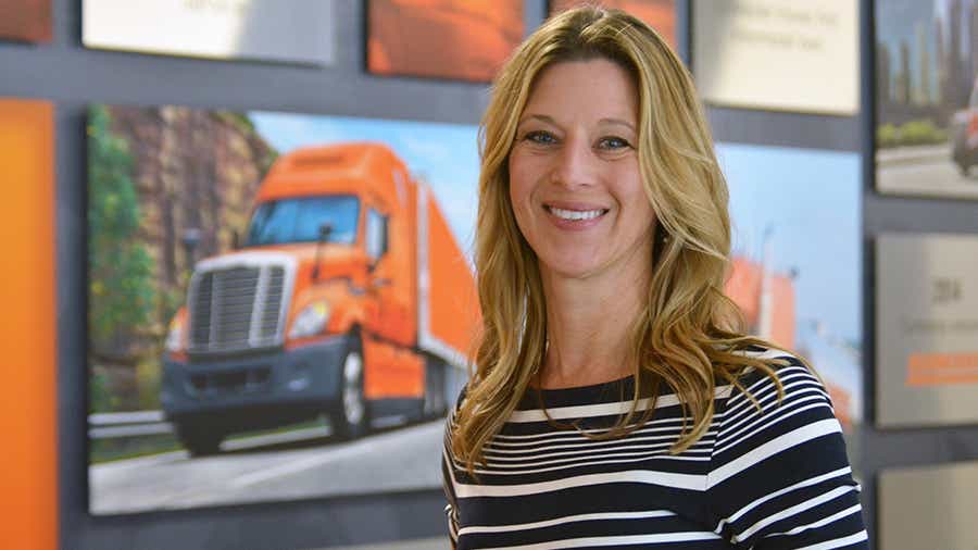 Julie Streich stands in front of Schneider's timeline wall that displays old truck photos