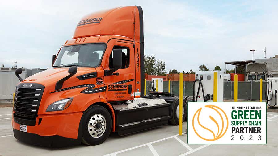 Schneider eCascadia electric trucks parked next to a charging station at their Southern California facility