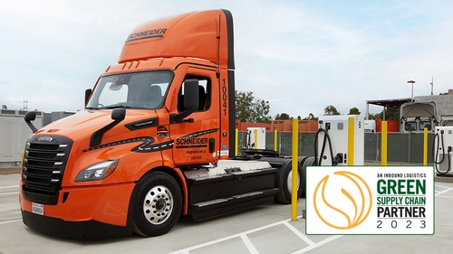 One of Schneider's eCascadia electric trucks parked next to a charging station at their Southern California facility, with the 2023 Inbound Logistics Green Supply Chain Parter logo in the bottom corner.
