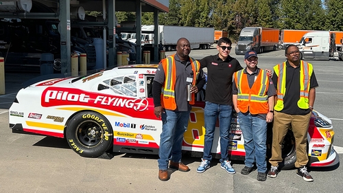 Nascar xfinity driver, Sammy Smith, stands in front of his car with three Schneider drivers