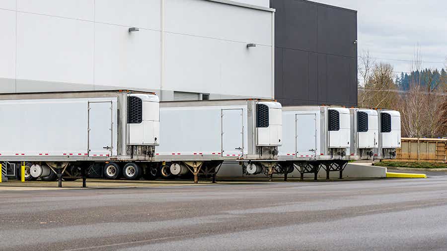 A row of refrigerated trailers at loading docks at a warehouse