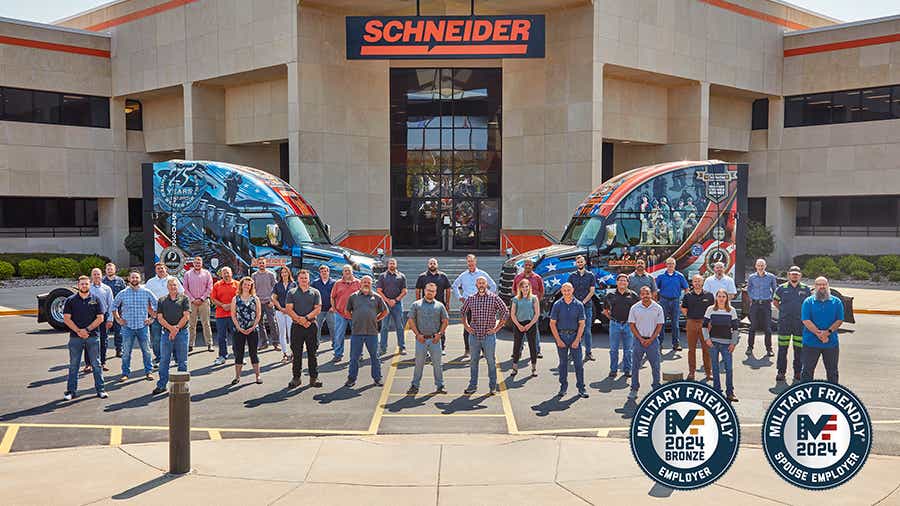 A large group of Schneider associates that are also military veterans or current military members stand outside of Schneider