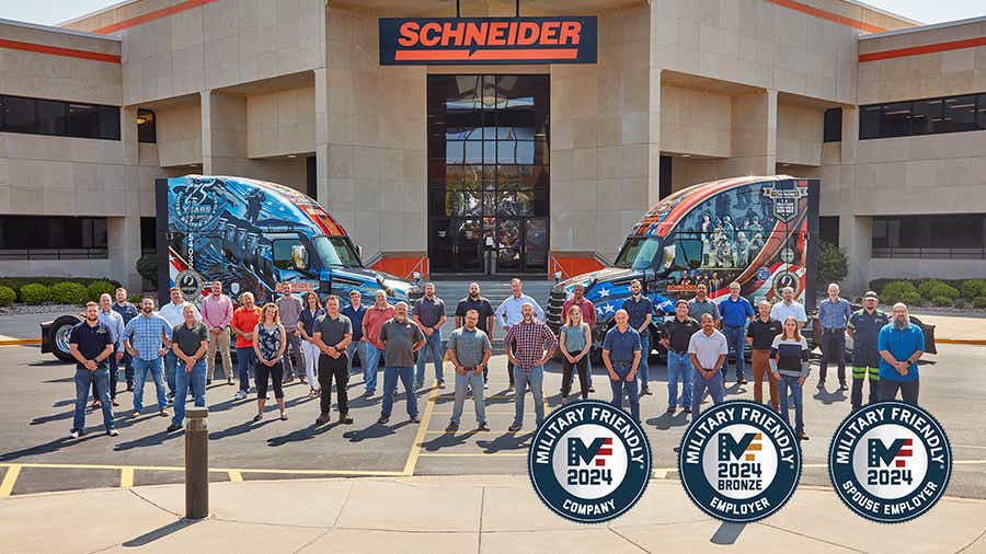 A large group of Schneider associates that are also military veterans or current military members stand outside of Schneider