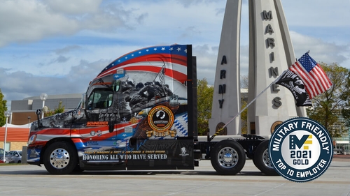 One of Schneider's Ride of Pride (patriotically decorated) tractors is parked besides a memorial to the U.S. Armed Forces.