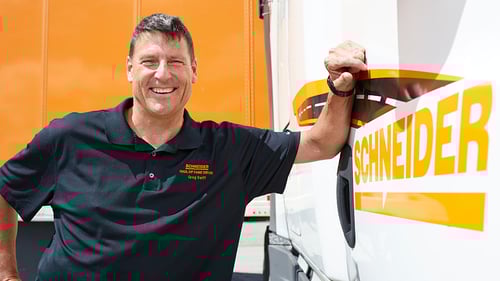 Schneider 5 million safe mile driver, Greg Swift, leans against the passenger side door of his semi truck