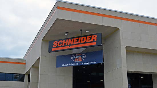The front of Schneider's corporate office with Schneider logo-ed sign and a banner below it with a 90th anniversary logo