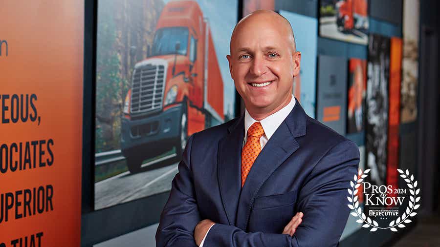Jason Howe stands in front of a photo of a Schneider truck at Schneider's corporate office.