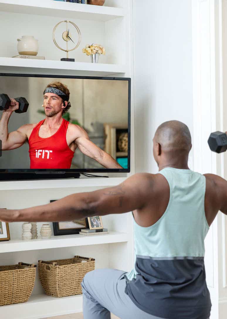 Man working out with dumbbells in front of TV