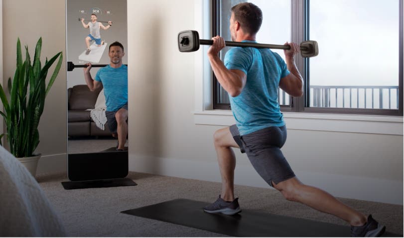 Man doing lunges with barbell in front of ProForm mirror