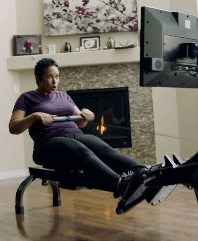 Woman intensely rowing on iFIT rowing machine.
