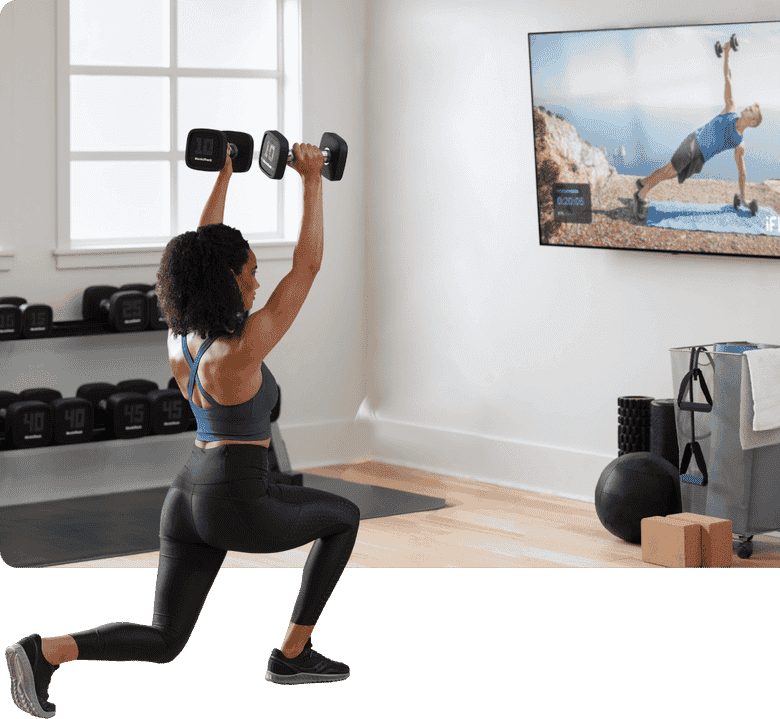 Woman exercises with dumbells while watching iFIT on TV