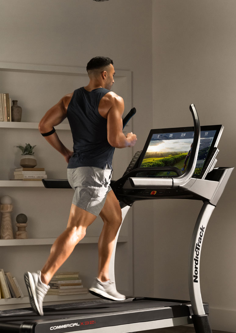 Man running on iFIT treadmill in front of bookshelf