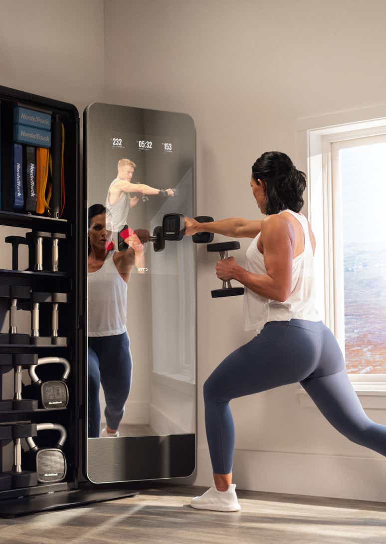 Woman exercises in front of a fitness mirror in living room
