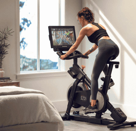 Woman does an iFIT workout class on her bike