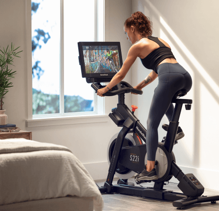 Woman does an iFIT workout class on her bike