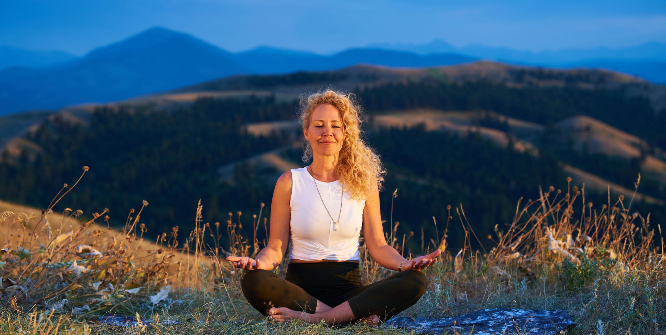 Woman meditates on blanket in a field