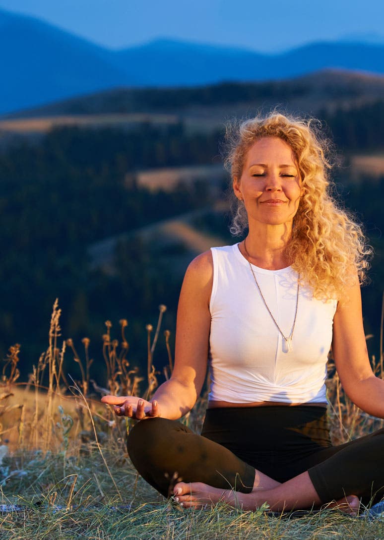 Woman meditates on blanket in a field