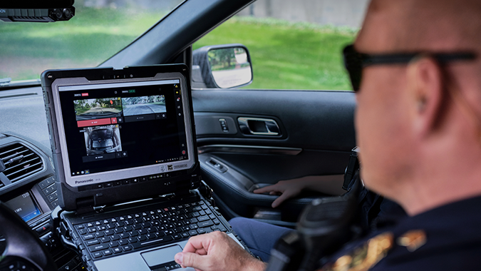 Police officer monitors live camera feeds on a rugged laptop inside a public safety vehicle