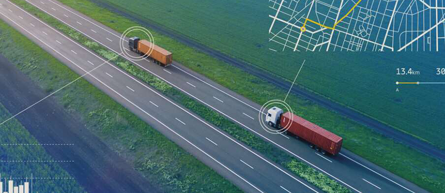 Two semi trucks driving on a long stretch of road.