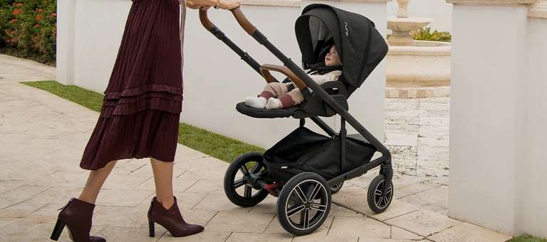 Mother in red dress pushing Nuna pram into her home