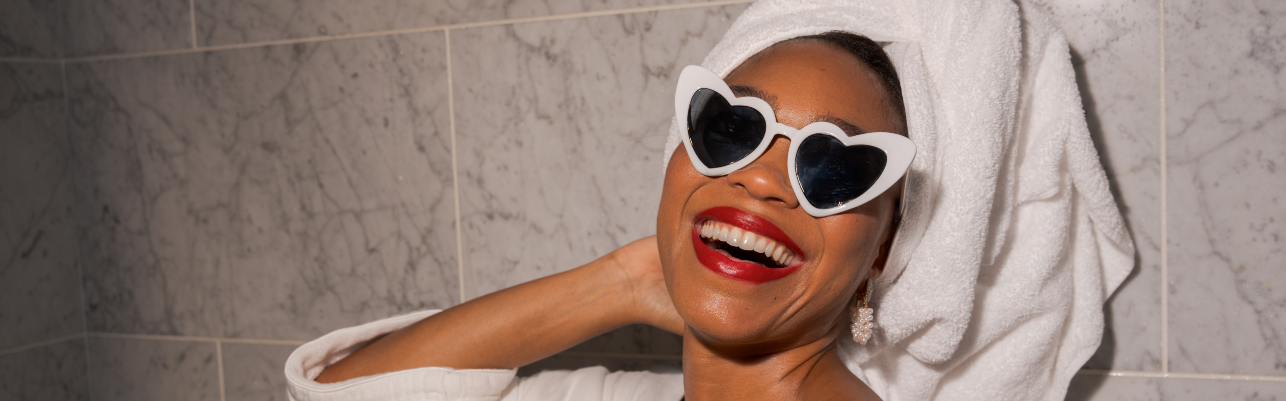Girl in hotel room with sunglasses and towel on head