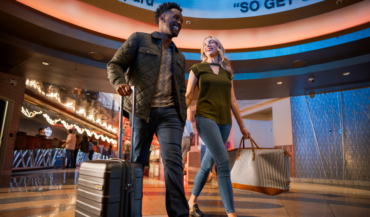 Two people walking with in the casino with overnight bags